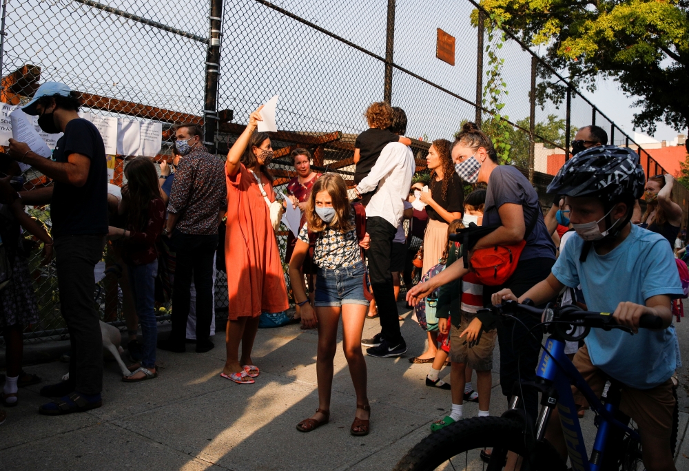 Students and parents gather in front of a school on the first day of New York City schools, amid the coronavirus disease (COVID-19) pandemic in Brooklyn, New York, U.S. September 13, 2021. REUTERS/Brendan McDermid

