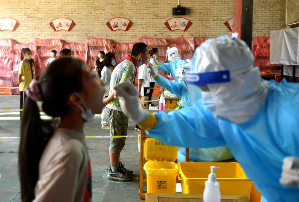 Medical workers wearing protective suits take swabs from primary school students at a nucleic acid testing site, following new cases of the coronavirus disease (COVID-19), in Fuzhou, Fujian province, China September 15, 2021. cnsphoto/via REUTERS