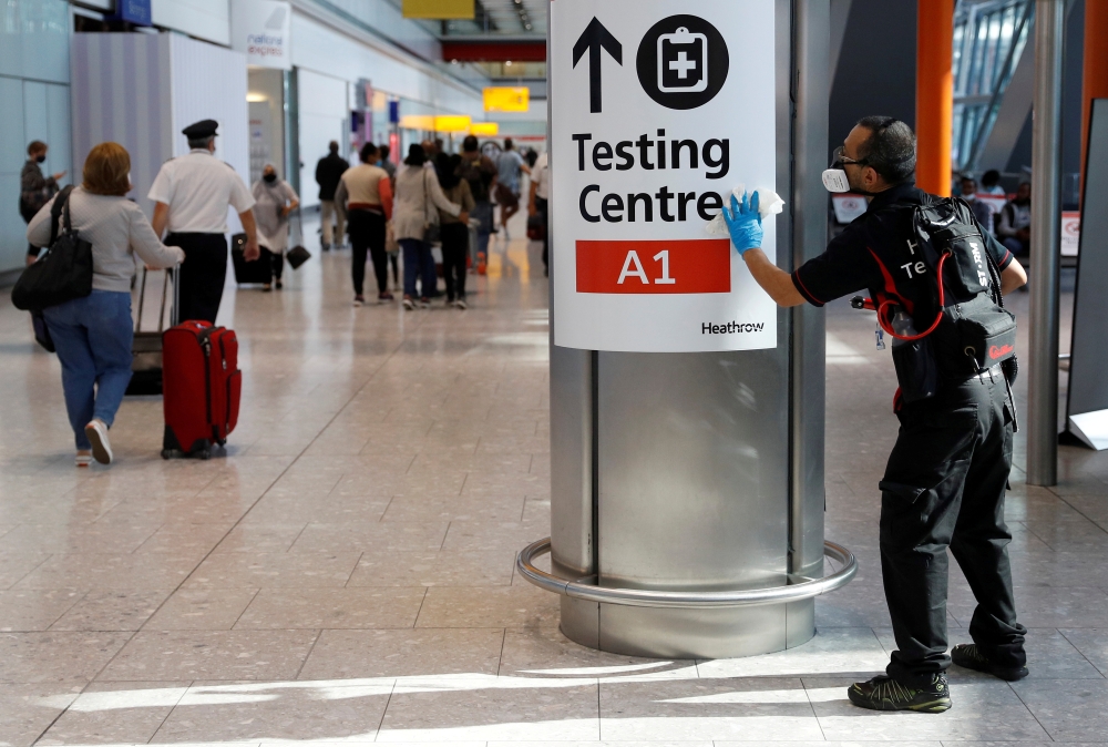 File photo: A worker sanitises a sign at the International arrivals area of Terminal 5 in London's Heathrow Airport, Britain, August 2, 2021. Reuters/Peter Nicholls/File Photo