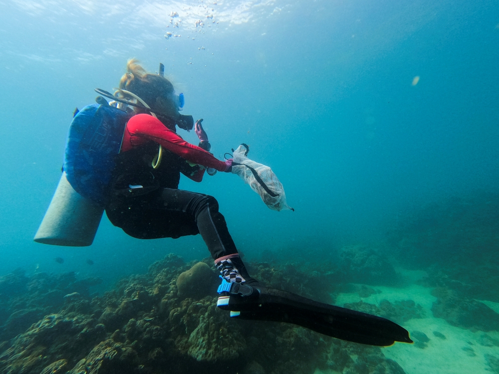 Diving instructor Carmela Sevilla holds a mesh bag filled with trash during a cleanup drive in Bauan, Batangas Province, Philippines, September 18, 2021. REUTERS/Peter Blaza