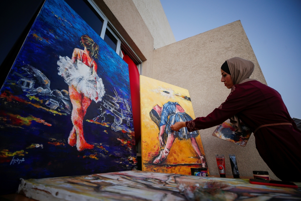A Palestinian artist, Abeer Jibril, works on ballet paintings at her home in Gaza City, September 8, 2021. Reuters/Mohammed Salem