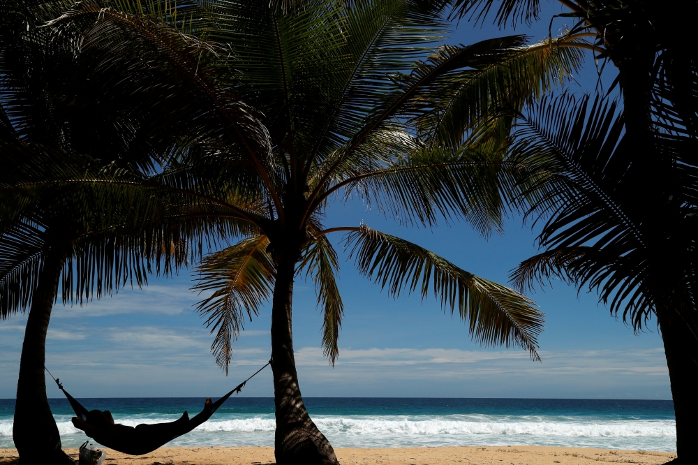 A man relaxes on Karon beach as Phuket gets ready to open to overseas tourists from July 1 allowing fully vaccinated foreigns to visit the resort island without quarantine, Phuket, Thailand June 29, 2021. REUTERS/Jorge Silva/File Photo