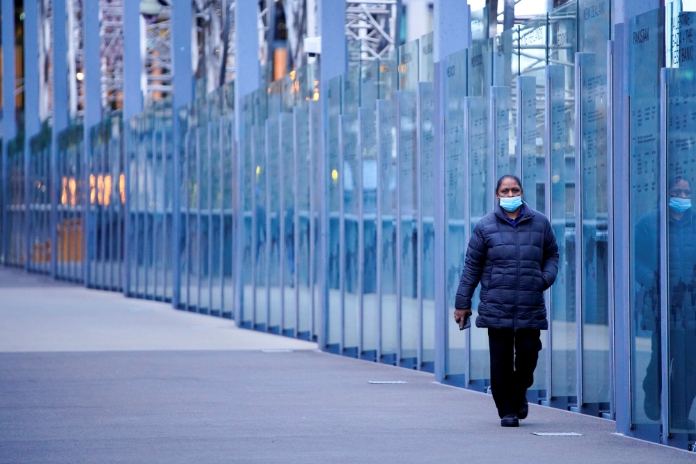 A woman wearing a protective face mask walks along a deserted city bridge during morning commute hours on the first day of a lockdown as the state of Victoria looks to curb the spread of a coronavirus disease (COVID-19) outbreak in Melbourne, Australia, J