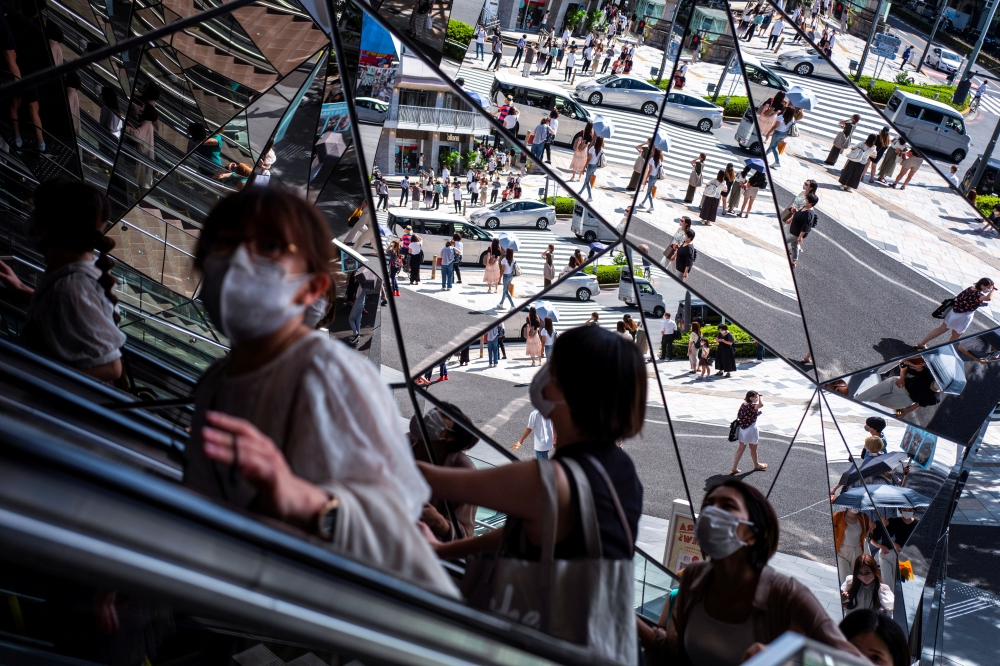 People wearing protective masks are reflected in the mirror at a shopping mall in Tokyo amid the coronavirus disease (COVID-19) outbreak in Tokyo, Japan, August 19, 2021. REUTERS/Athit Perawongmetha/File Photo