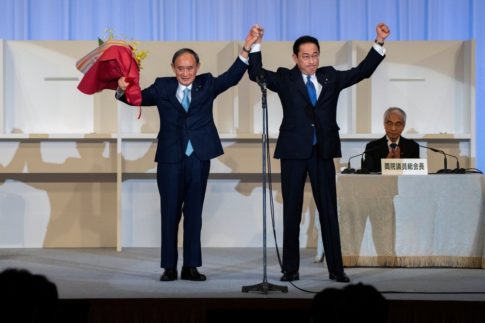 Former Japanese Foreign Minister Fumio Kishida celebrates with outgoing Prime Minister, Yoshihide Suga, after being announced the winner of the Liberal Democrat Party leadership election in Tokyo, Japan September 29, 2021. Carl Court/Pool via Reuters