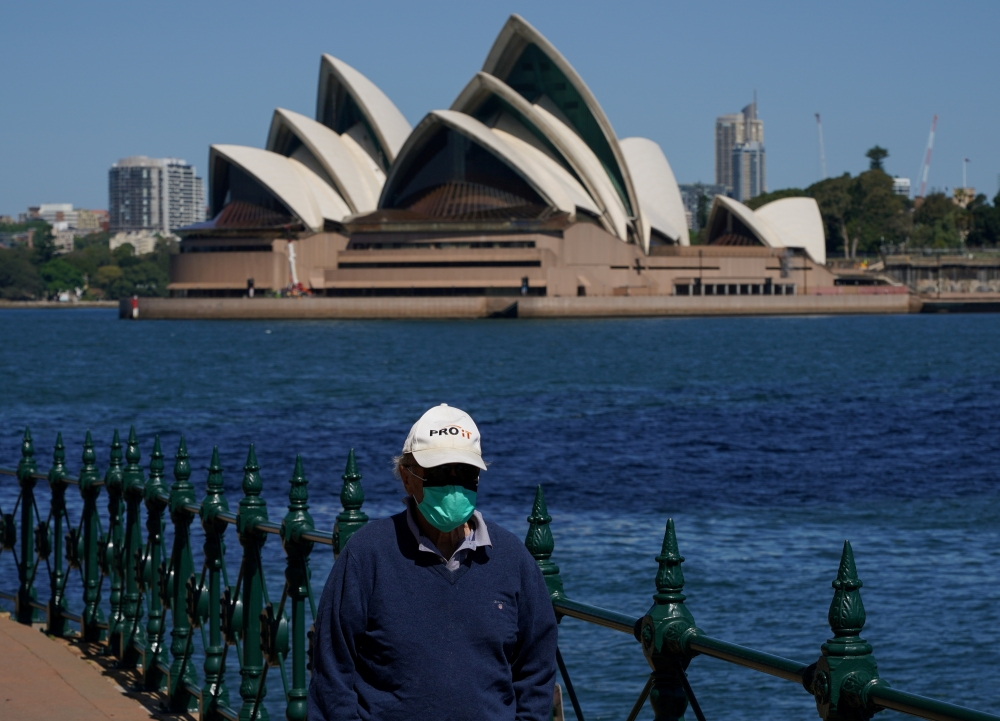 A person in protective face mask walks along the harbour waterfront across from the Sydney Opera House during a lockdown to curb the spread of coronavirus disease (COVID-19) outbreak in Sydney, Australia, October 6, 2021. REUTERS/Loren Elliott/File Photo