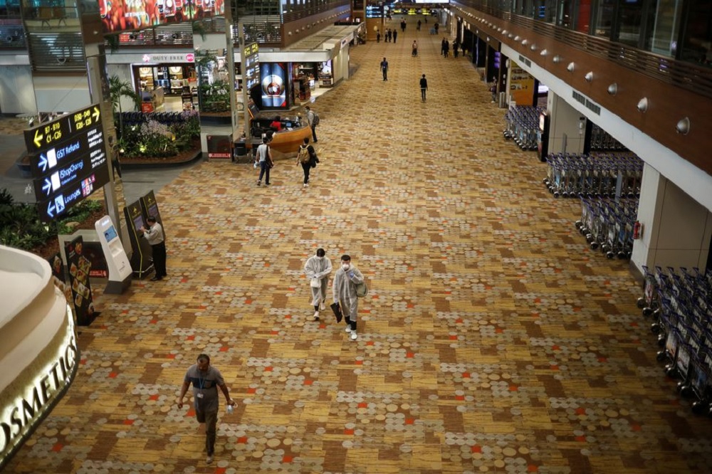 People, some of them wearing protective face masks, walk at Singapore's Changi Airport, following the outbreak of the coronavirus disease (COVID-19) March 30, 2020. REUTERS/Edgar Su