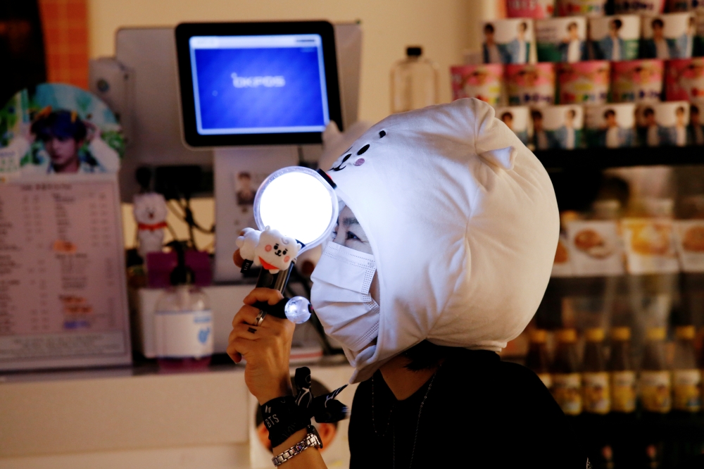 A fan of K-pop idol boy band BTS watches a live streaming online concert, wearing a protective mask to avoid the spread of the coronavirus disease (COVID-19), at a cafe in Seoul, South Korea October 10, 2020. REUTERS/Heo Ran/File Photo