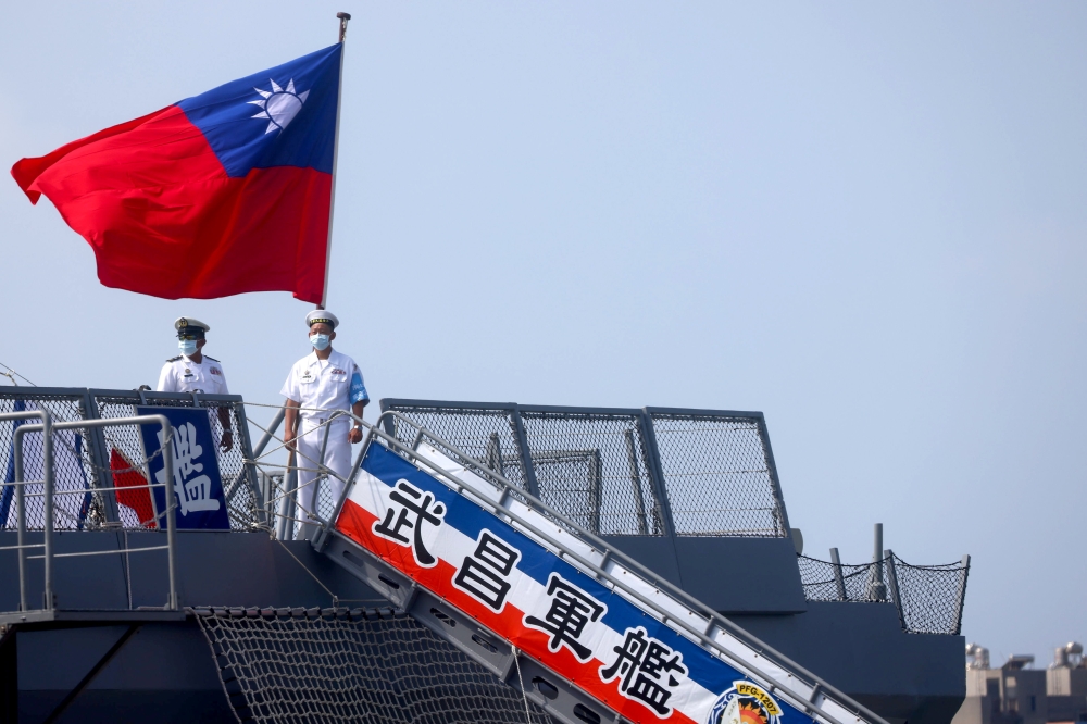 Two navy soldiers stand next to a Taiwanese flag as they welcome members of the public during a visit on the French-built ROCS Wu Chang (PFG-1207) frigate ahead of the National Day celebration in Kaohsiung, Taiwan, October 9, 2021. Reuters/Ann Wang