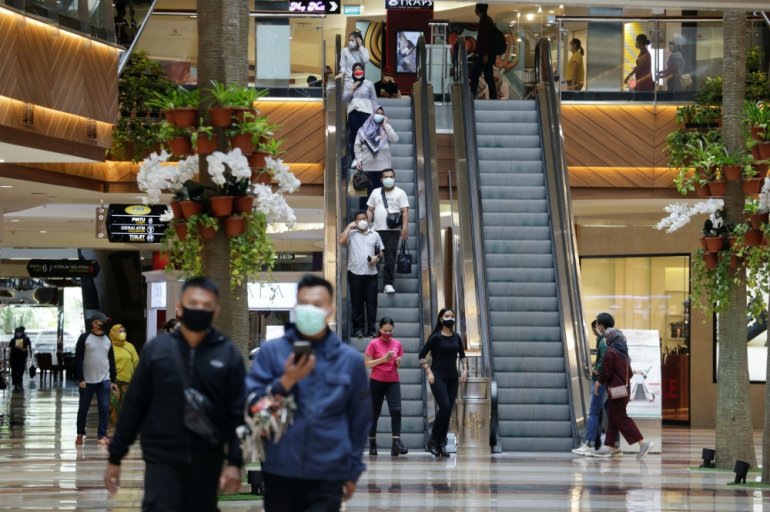 People wearing protective face masks walk at the Pondok Indah shopping mall, as the Indonesian capital reopens shopping malls with a new policy requiring shoppers to show a coronavirus disease (COVID-19) vaccination certificate, in Jakarta, Indonesia, Aug