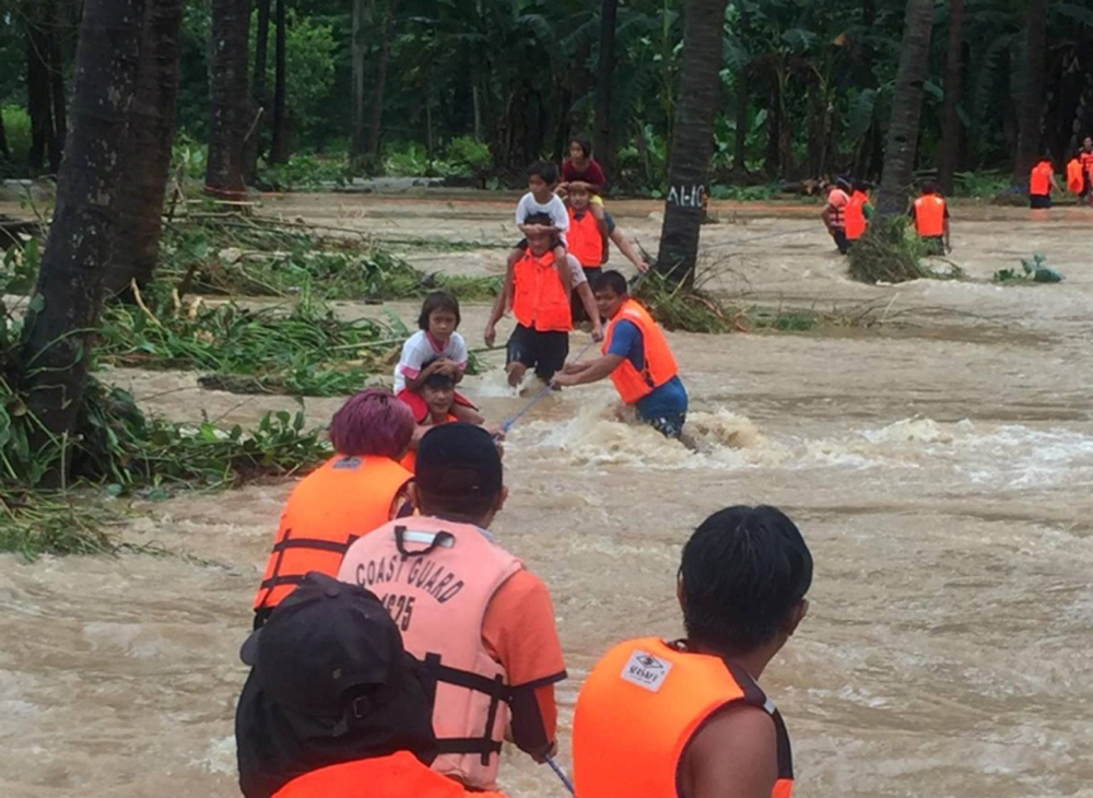 People cross floodwaters caused by tropical cyclone Kompasu during an evacuation assisted by the Philippine Coast Guard (PCG) at Brooke's Point, Palawan, in the Philippines, Ocotober 12, 2021, in this image obtained via social media. Philippine Coast Guar