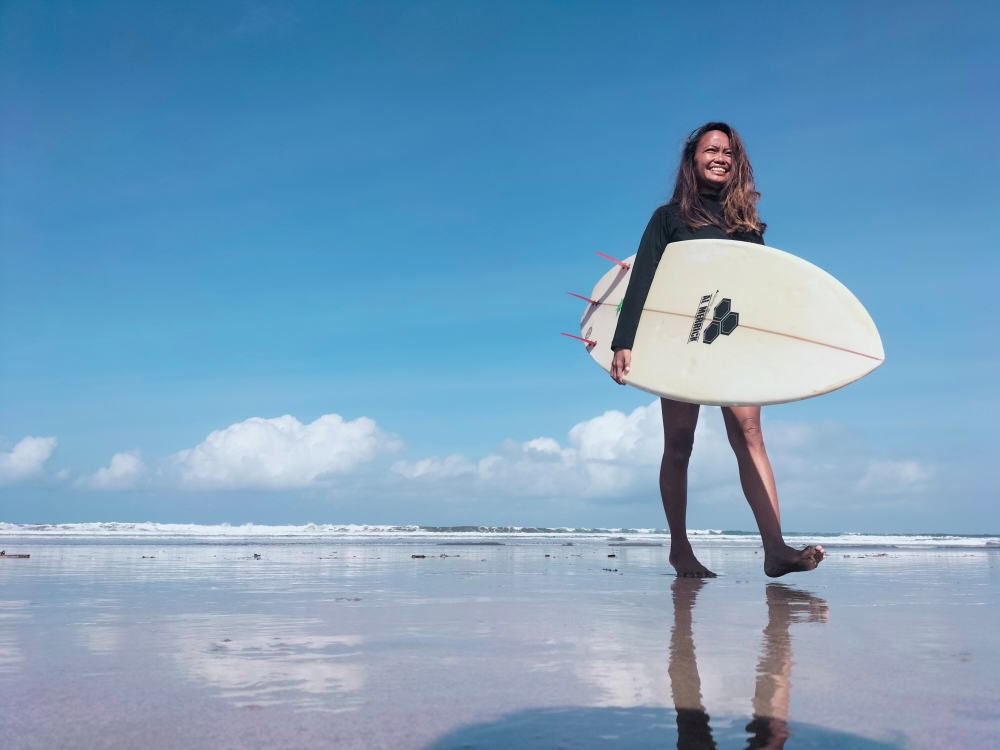 A surfing business owner, 38-year-old, Halfia Lando poses holding a surfboard at a Kuta beach as Indonesia opens up the tourist island of Bali to some countries. Reuters/Sultan Anshori 