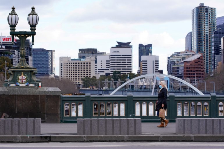 A lone woman, wearing a protective face mask, walks across an unusually quiet city centre bridge on the first day of a lockdown as the state of Victoria looks to curb the spread of a coronavirus disease (COVID-19) outbreak in Melbourne, Australia, July 16