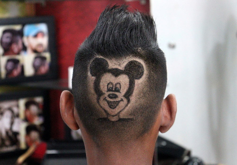 A customer poses for a photograph after he has his head shaved in the shape of Mickey Mouse by barber Rajwinder Singh Sidhu inside his shop in Dabwali town, in the northern state of Punjab, India, October 12, 2021. Picture taken October 12, 2021. REUTERS/