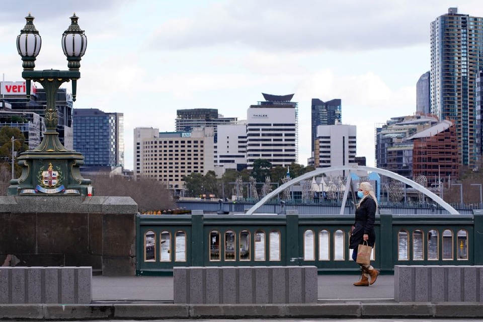 A lone woman, wearing a protective face mask, walks across a city centre bridge as the state of Victoria looks to curb the spread of a coronavirus disease (COVID-19) outbreak in Melbourne, Australia, July 16, 2021. REUTERS/Sandra Sanders/File Photo