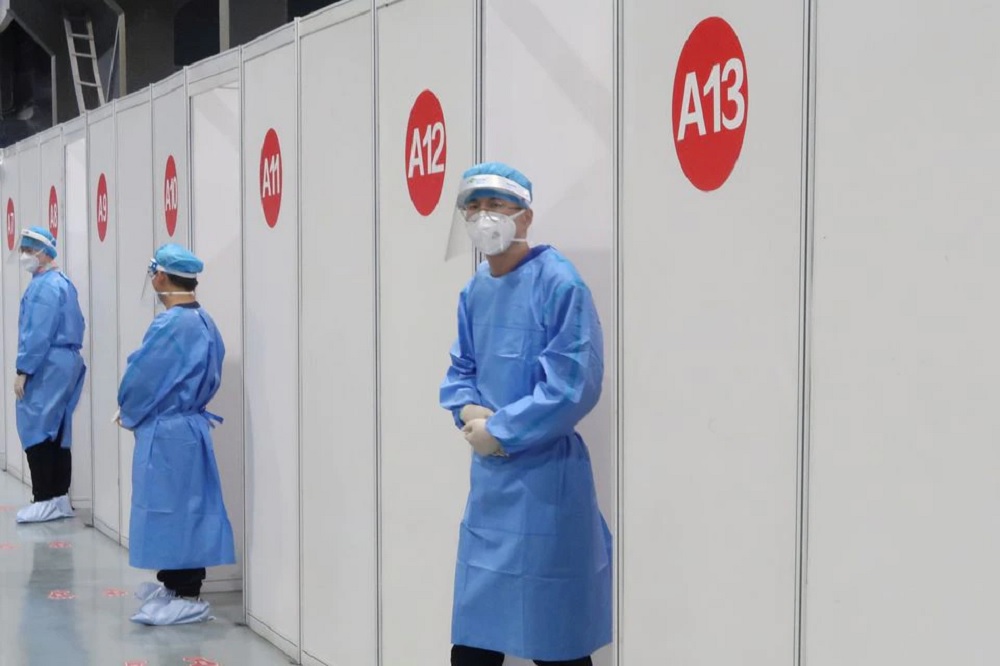 Staff members wait outside booths where people receive a vaccine against the coronavirus disease (COVID-19) at a vaccination center, during a government-organized visit, in Beijing, China, April 15, 2021. REUTERS/Thomas Peter