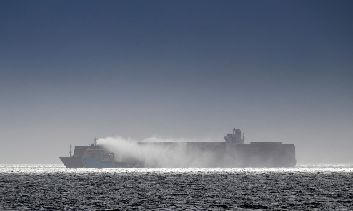 Salvage tug boats spray what appears to be water onto the container ship Zim Kingston after the crew were evacuated due to a fire on board, in Victoria, British Columbia, Canada October 24, 2021. REUTERS/Kevin Light
