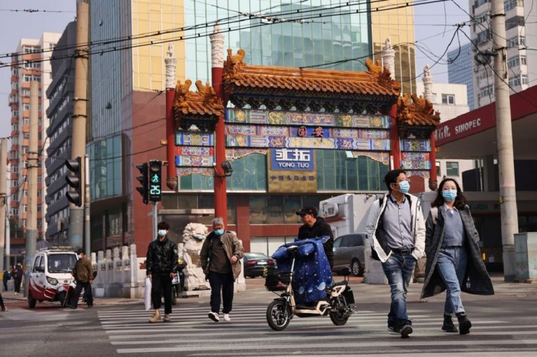 People wearing face masks cross a street in Beijing, following outbreaks of the coronavirus disease (COVID-19) in China, October 25, 2021. REUTERS/Thomas Peter