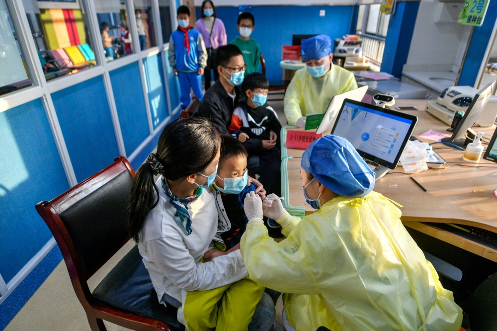 A medical worker administers a dose of a coronavirus disease (COVID-19) vaccine to a child in Huzhou, Zhejiang province, China October 26, 2021. Picture taken October 26, 2021. China Daily via REUTERS