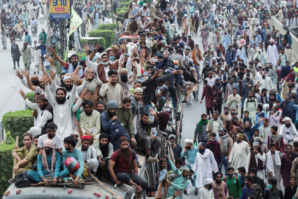 Supporters of the banned Islamist political party Tehrik-e-Labaik Pakistan (TLP) stand atop of a vehicle while others walk during a protest, in Lahore, Pakistan, October 23, 2021. Reuters/Mohsin Raza/File Photo