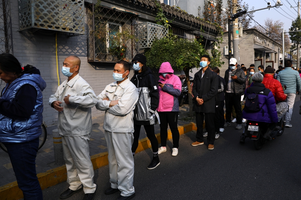 People line up outside a vaccination site after the city started offering booster shots of the vaccine against the coronavirus disease (COVID-19) to vaccinated residents, in Beijing, China October 29, 2021. (REUTERS/Tingshu Wang)