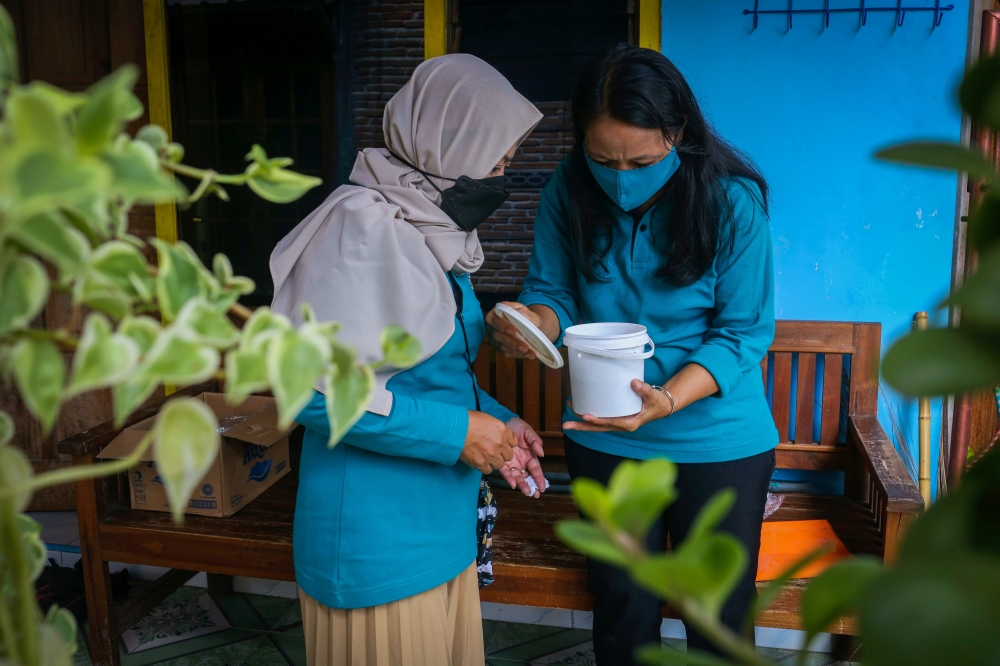 Volunteers of the World Mosquitoes Program (WMP) check the Wolbachia mosquito hatchery bucket at a house in Yogyakarta, Indonesia, October 13, 2021. Reuters/Dwi Oblo