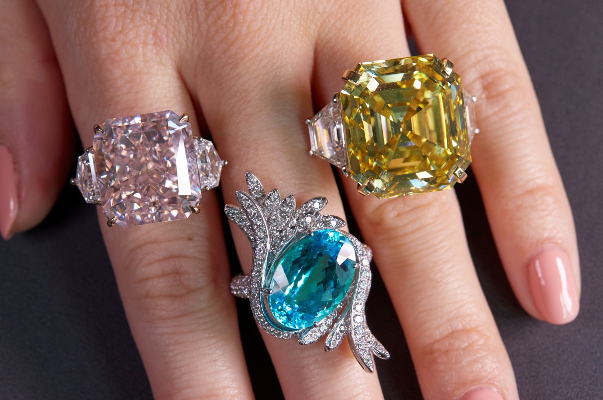 A staff wears an orange-pink diamond ring weighing 25.62 carats, a tourmaline and diamond ring weighing 9.88 carats and a yellow diamond ring weighing 25.88 carats, during a preview at Sotheby?s, before their auction sale in Geneva, Switzerland, November 2, 2021. REUTERS/Denis Balibouse
