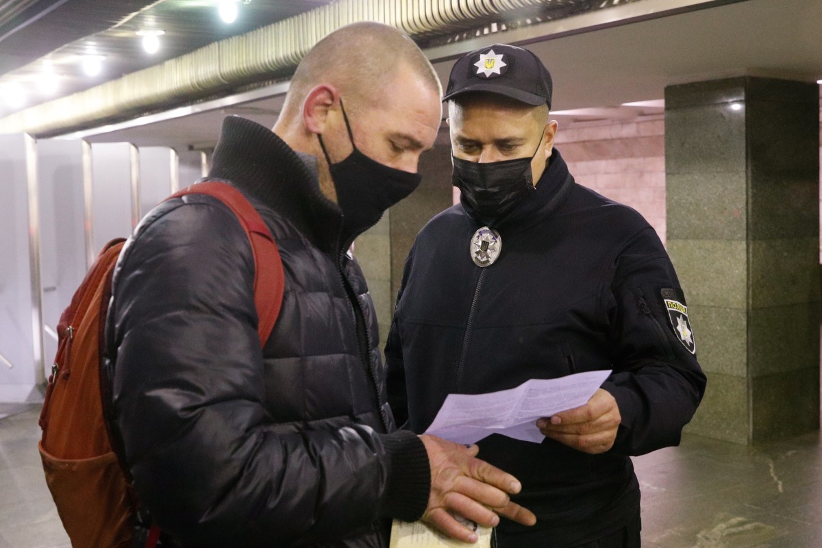 A police officer checks a certificate of vaccination against the coronavirus disease (COVID-19) or a negative COVID-19 test of a passenger at a subway station, after new restrictions were imposed by local authorities to curb the spread of the coronavirus disease (COVID-19), in Kyiv, Ukraine November 1, 2021. REUTERS/Valentyn Ogirenko
