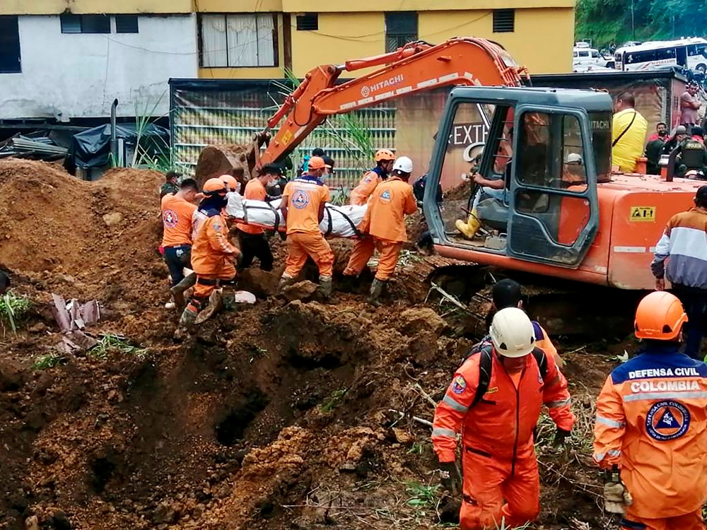 Colombian Civil Defense workers unearth the body of a deceased person in a landslide that was caused by heavy rains in the country, in Mallana, Colombia November 2, 2021. Colombian Civil Defense/Handout via REUTERS