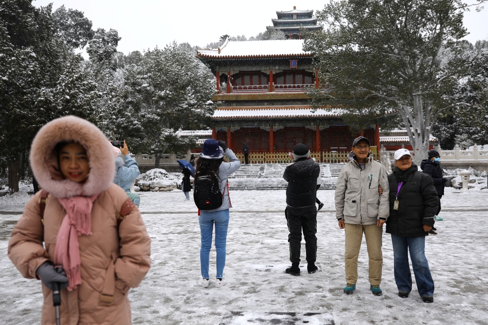 People enjoy snowfall at Jingshan Park, in Beijing, China November 7, 2021. REUTERS/Tingshu Wang