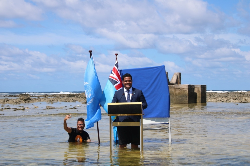 Tuvalu's Minister for Justice, Communication & Foreign Affairs Simon Kofe gives a COP26 statement while standing in the ocean in Funafuti, Tuvalu November 5, 2021. Courtesy Tuvalu's Ministry of Justice, Communication and Foreign Affairs / Social Media via Reuters