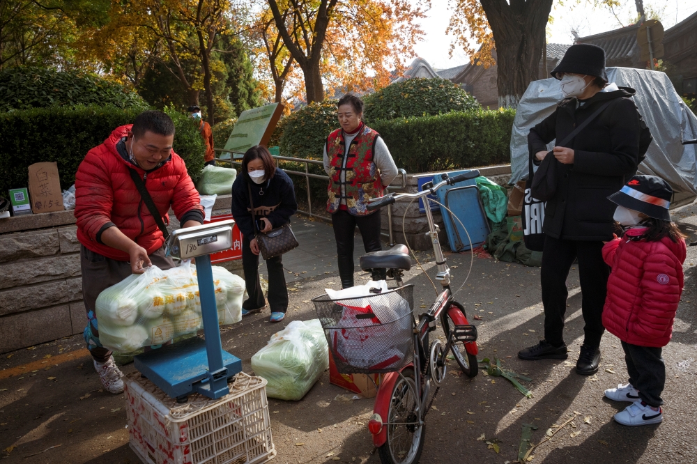 People buy cabbage at a street stall, an annual tradition in winter that has taken on extra importance after the government advised people to keep enough basic goods at home in case of emergencies, following outbreaks of the coronavirus disease (COVID-19) in Beijing, China, November 4, 2021. REUTERS/Thomas Peter