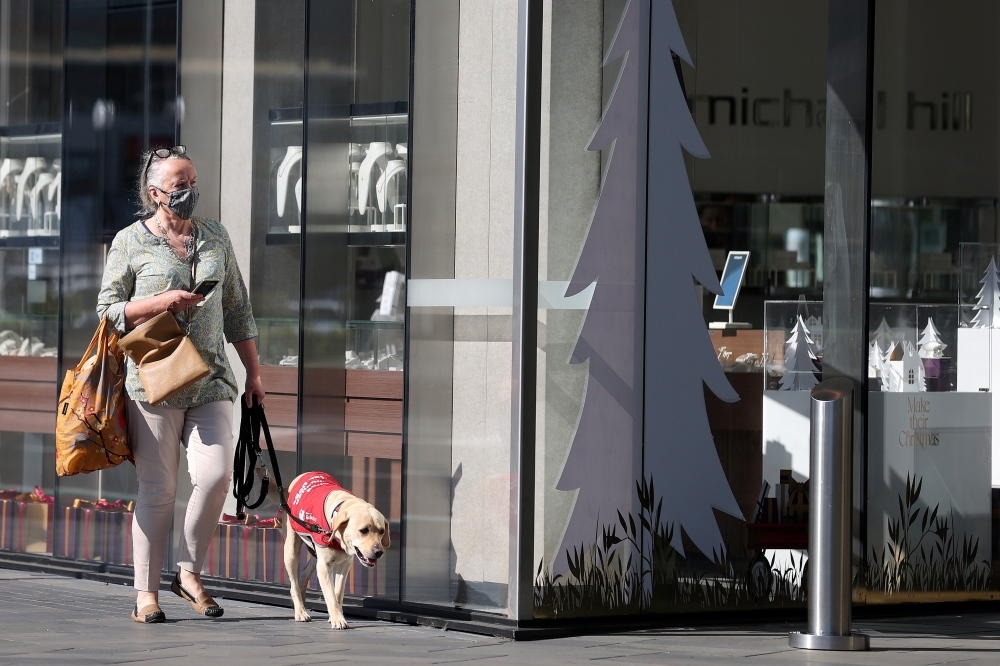 A pedestrian wearing a face mask walks past a storefront as shoppers return to the Newmarket retail district in the wake of coronavirus disease (COVID-19) lockdown restrictions being eased in Auckland, New Zealand, November 10, 2021. REUTERS/Fiona Goodall