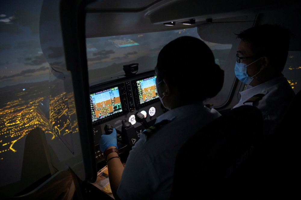 Cadet Casey Abadilla, a flight student, operates a flight simulator beside an instructor, both wearing masks for protection against the coronavirus disease (COVID-19), at the Alpha Aviation Group campus in Clark, Pampanga province, Philippines, November 3, 2021. REUTERS/Eloisa Lopez