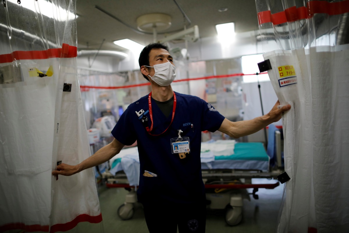 FILE PHOTO: St. Marianna University Yokohama Seibu Hospital department of emergency and critical care medicine doctor Hiroki Saito draws plastic curtain at emergency and critical care room inside the hospital where patients suffering from the coronavirus disease (COVID-19) are being treated in Yokohama, south of Tokyo, Japan May 25, 2021. Picture taken May 25, 2021. REUTERS/Issei Kato/File Photo
