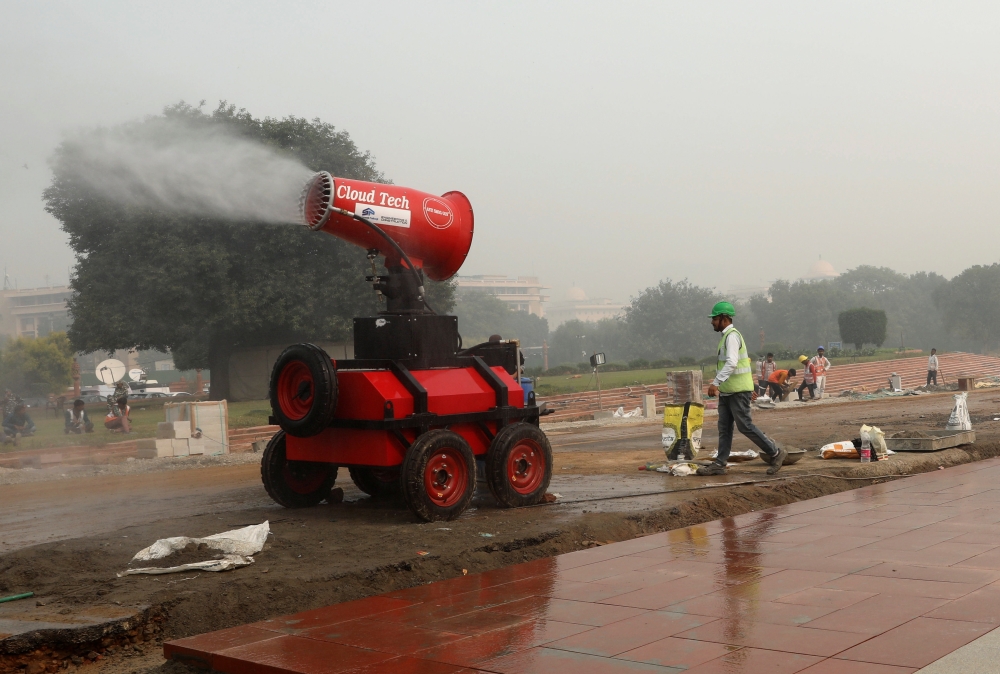 A worker is seen next to an anti-smog gun near the ongoing redevelopment project on Rajpath, on a smoggy day in New Delhi, India, November 12, 2021. REUTERS/Anushree Fadnavis