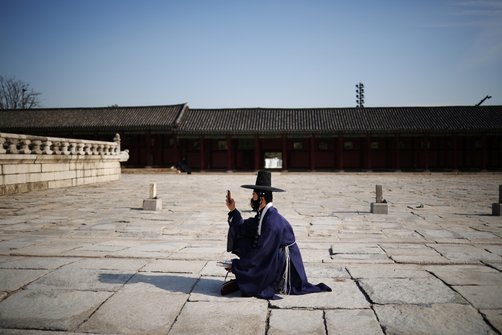 A man in Korean traditional costume Hanbok, wearing a protective face mask to avoid contracting the coronavirus disease (COVID-19), takes a photo of his girlfriend (not pictured) at Gyeongbok palace in Seoul, South Korea, November 17, 2021. REUTERS/Kim Hong-Ji
