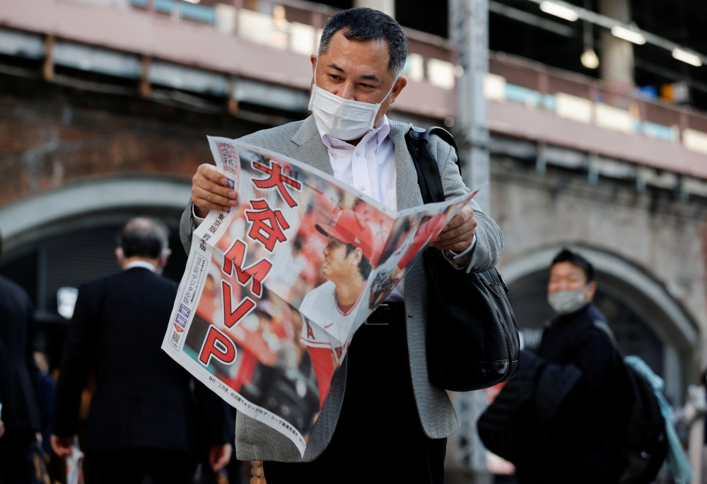 A man reads an extra edition of a newspaper, reporting Japan's Shohei Ohtani of the Los Angeles Angels was named Most Valuable Player of Major League Baseball's American League, in Tokyo, Japan November 19, 2021. REUTERS/Issei Kato