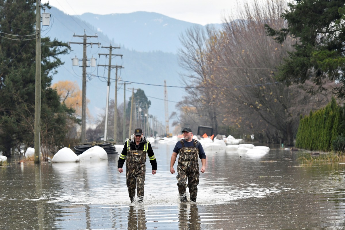Rob Feenstra and Brendan van Biert walk through flood water after conducting a hazard assessment at a local bio gas plant after rainstorms lashed the western Canadian province of British Columbia, triggering landslides and floods, shutting highways, in Abbottsford, British Columbia, Canada November 22, 2021. REUTERS/Jennifer Gauthier
