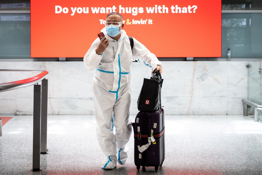 A traveller wearing personal protective equipment arrives at the international terminal at Sydney Airport, as countries react to the new Omicron variant of the coronavirus, in Sydney, Australia, November 29, 2021. AAP Image/James Gourley via REUTERS