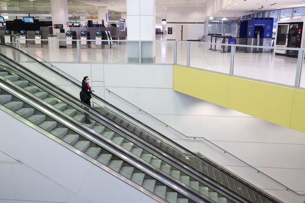 A flight crew member stands on an escalator in the international terminal at Sydney Airport, as countries react to the new coronavirus Omicron variant amid the coronavirus disease (COVID-19) pandemic, in Sydney, Australia, November 30, 2021. REUTERS/Loren Elliott