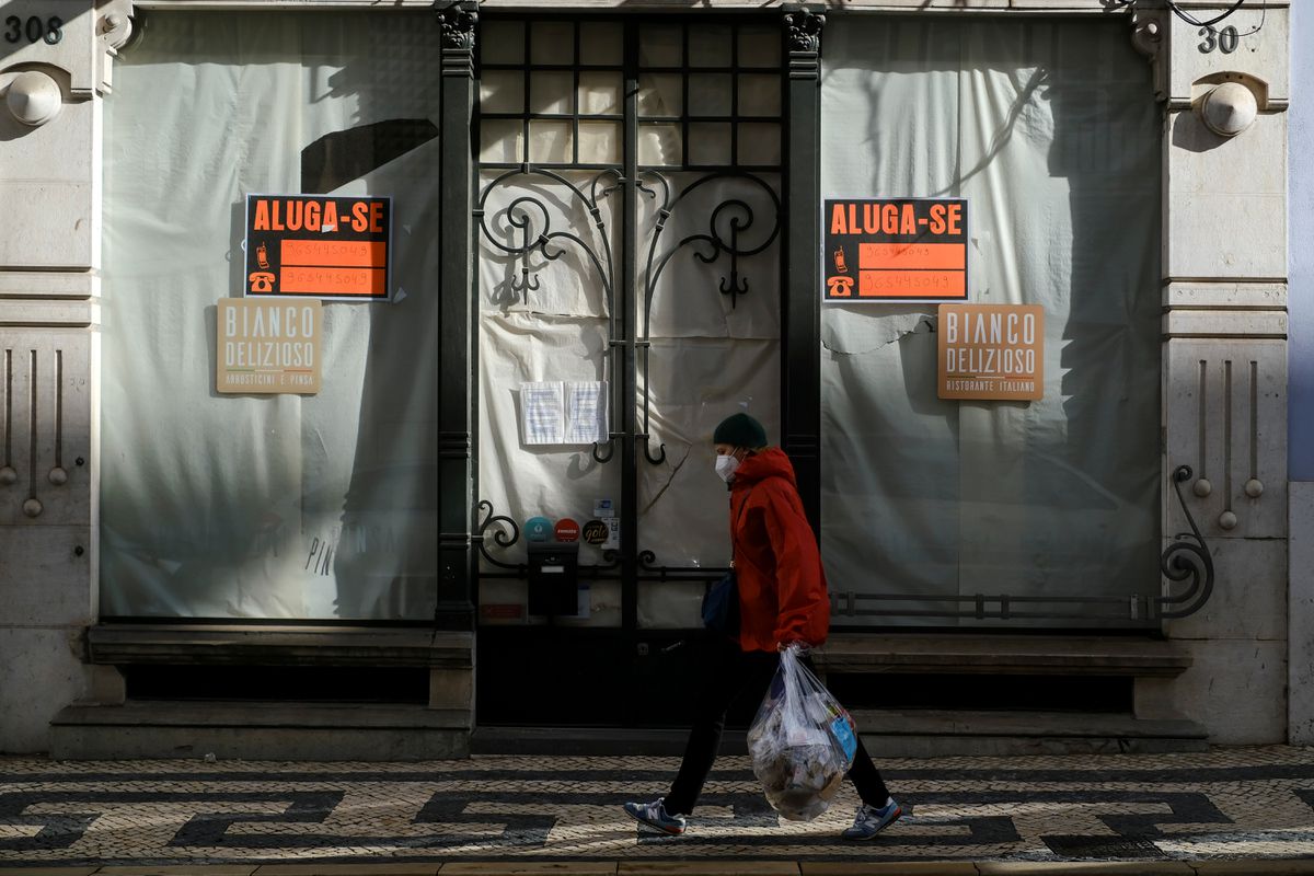 A woman wearing a protective mask due to coronavirus disease (COVID-19) pandemic walks past a closed store in central Lisbon, Portugal, November 25, 2021. REUTERS/Pedro Nunes

