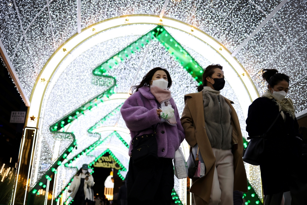 Women wearing masks to prevent contracting the coronavirus disease (COVID-19) walk under a Christmas illumination at a shopping district in central Seoul, South Korea, December 1, 2021. REUTERS/Kim Hong-Ji/File Photo