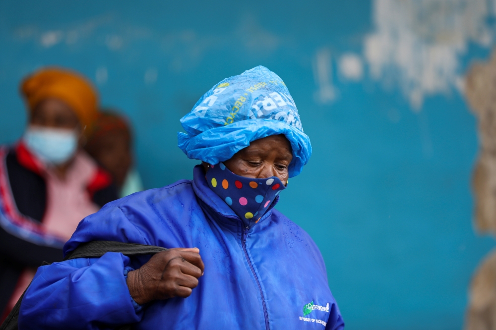 A woman wearing a protective face mask against the coronavirus disease (COVID-19) and a plastic bag on her head to protect from the rain looks on, as the new Omicron coronavirus variant spreads, at Tsomo, a town in the Eastern Cape province of South Africa, December 2, 2021. Picture taken December 2, 2021. REUTERS/Siphiwe Sibeko
