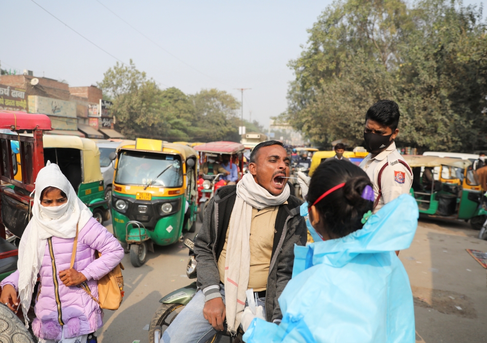 A healthcare worker collects a coronavirus disease (COVID-19) test swab sample from a man on a road in New Delhi, India, December 6, 2021. REUTERS/Anushree Fadnavis