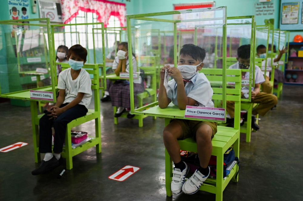 Students seated on chairs with plastic barriers attend a class as several schools in the Philippines' capital reopen for the first time since the coronavirus disease (COVID-19) pandemic, in Pasay City, Metro Manila, Philippines, December 6, 2021. REUTERS/Lisa Marie David