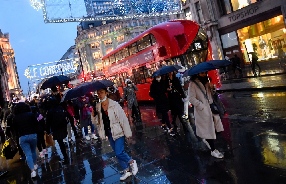Shoppers hold umbrellas as they walk, following the outbreak of the coronavirus disease (COVID-19), at Oxford Street in London, Britain December 16, 2020. REUTERS/Toby Melville/File Photo GLOBAL BUSINESS WEEK AHEAD