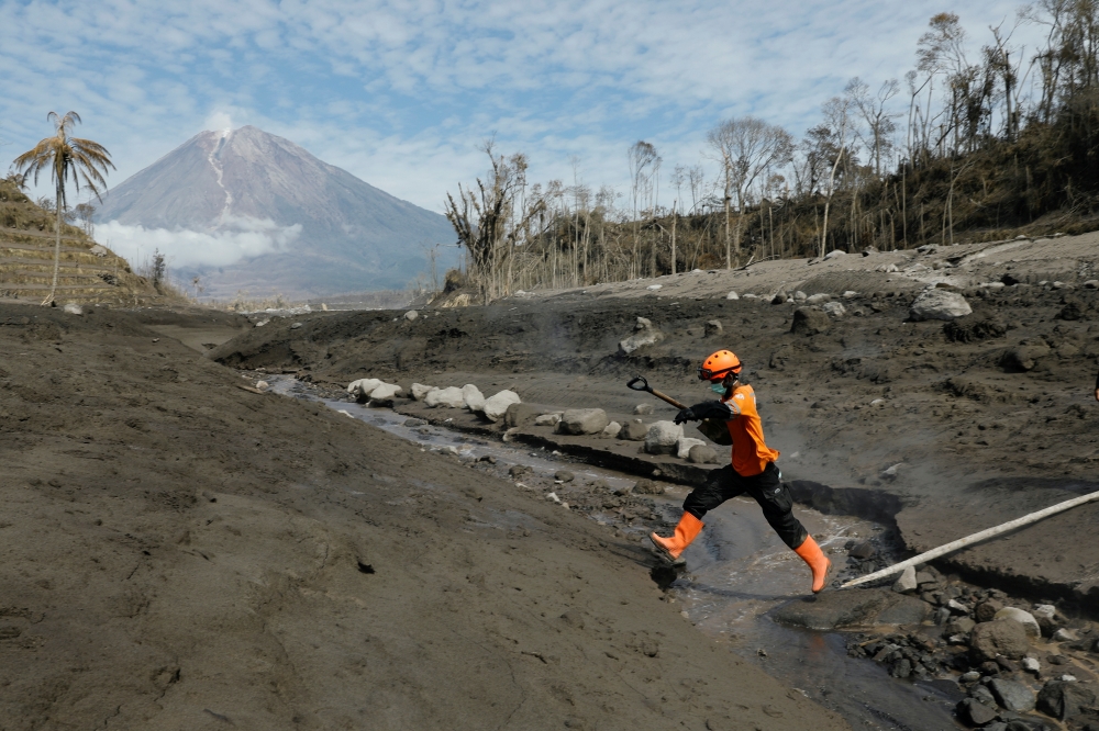 A rescue worked jumps across the lava flow path during an operation at an area affected by the eruption of Mount Semeru volcano, in Curah Kobokan, Pronojiwo district, Lumajang, East Java province, Indonesia, December 8, 2021. REUTERS/Willy Kurniawan