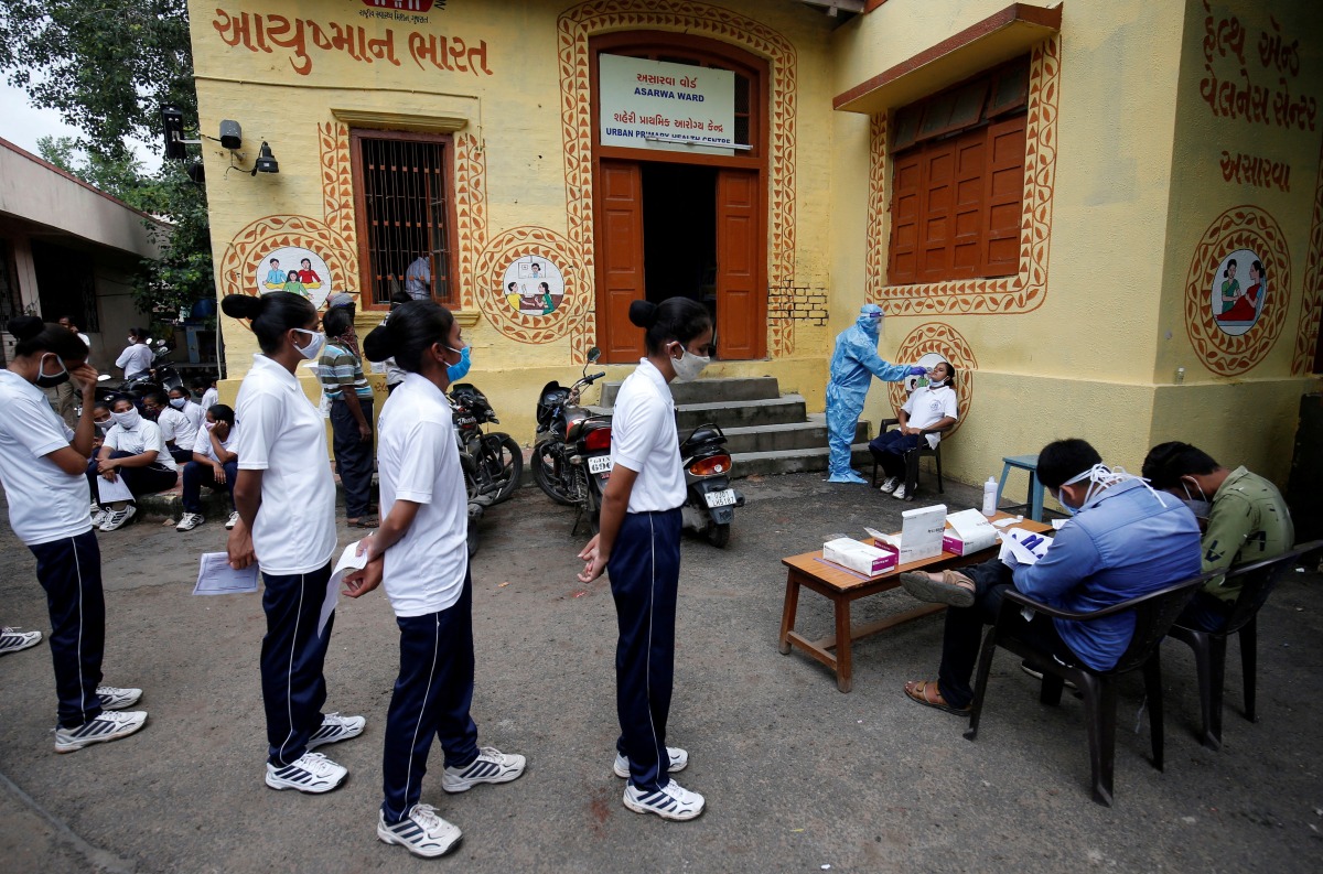 FILE PHOTO: A healthcare worker wearing personal protective equipment (PPE) takes a swab from a police officer for a rapid antigen test as others line up at a special testing center for Gujarat Police, amid the coronavirus disease (COVID-19) outbreak, in AHMEDABAD, India, August 17, 2020. REUTERS/Amit Dave/File Photo
