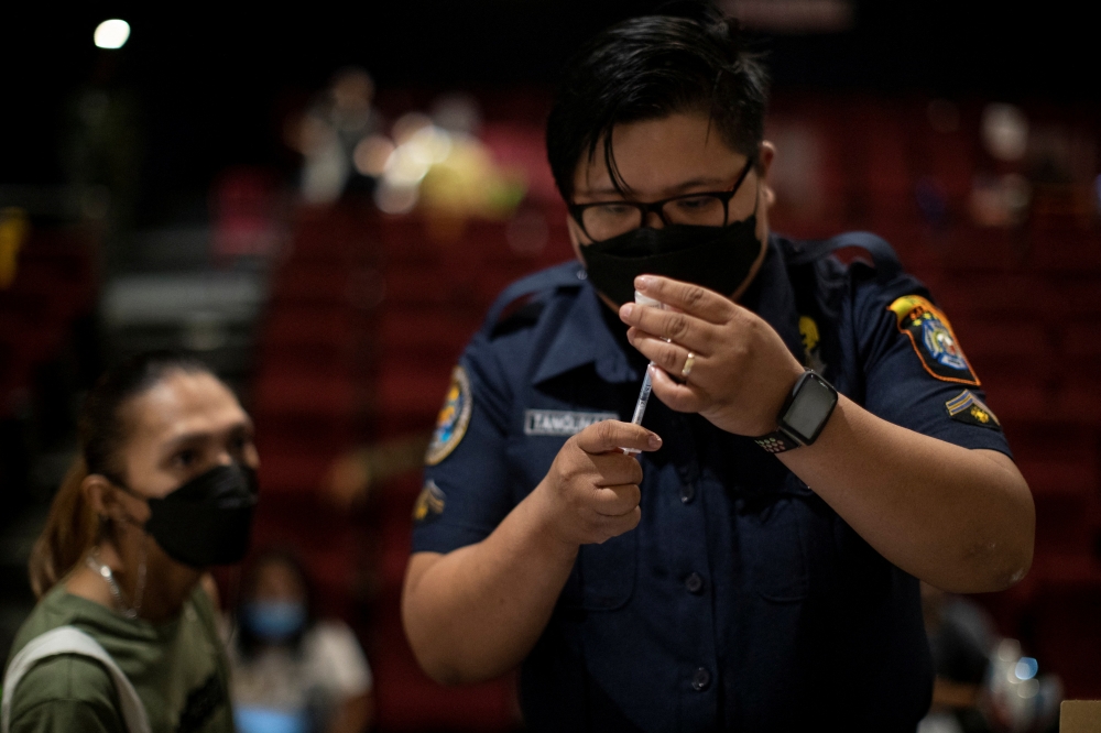 A health worker prepares a dose of COVID-19 vaccine for protection against the coronavirus disease at a cinema turned into a temporary vaccination site in San Juan, Metro Manila, Philippines, December 15, 2021. Reuters/Eloisa Lopez
